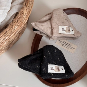 Detail of knitted beanies in black and beige with floral patterns and bear embroidery