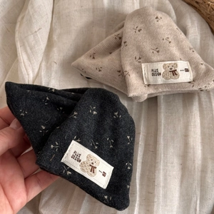 Close-up of baby knitted hats in dark grey and beige with floral patterns and bear labels