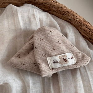 Detailed close-up of a floral baby knit hat featuring a cute bear patch in a wicker basket