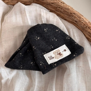 Detail of dark grey knit beanie with floral embroidery and cute bear patch label