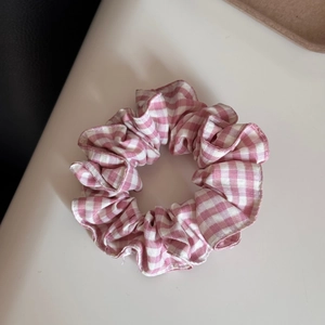 Detailansicht eines rosa-weiß karierten Haargummis aus Stoff mit Rüschentextur