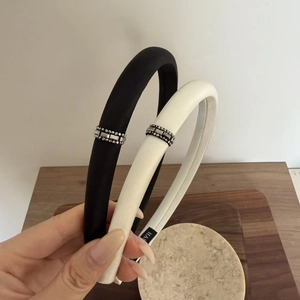 Détail de serre-têtes en satin noir et crème avec bordure latérale en strass brillants
