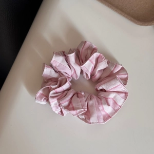 Detailansicht eines rosa-weiß gestreiften Stoff-Haargummis mit weicher Textur