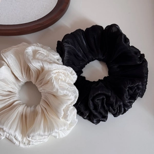 Detail of pleated satin scrunchies in black and cream white with elegant textures
