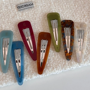 Flat lay of 7-piece candy-colored acetate hair clips on soft white fleece background