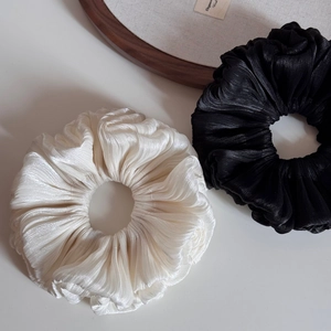 Detail of elegant pleated scrunchies in black and beige with soft satin texture