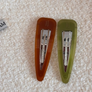 Detail of amber and olive green acetate teardrop hair clips with handmade engraving