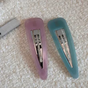 Detail of matte waterdrop hair clips in pink and blue on white fleece texture