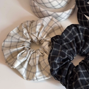 Close-up of black and white plaid fabric scrunchies and matching headband set on white background