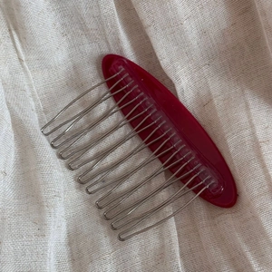 Detail view of burgundy acrylic decorative hair comb with fifteen silver metal teeth