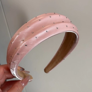 Détail d'un serre-tête large en satin rose avec strass brillants pour un style élégant