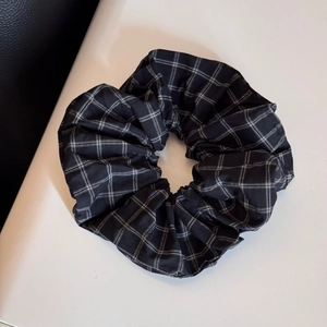 Detail of a large black and white checkered scrunchie showing fine fabric texture and pleats