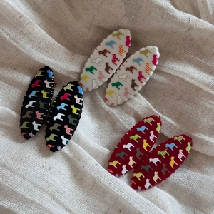 Close-up of six wavy-edged hair clips in black, white, and red with animal prints