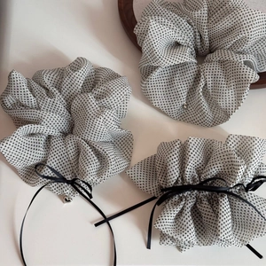 Detailed view of white polka dot tulle scrunchie with a silver heart pendant accessory