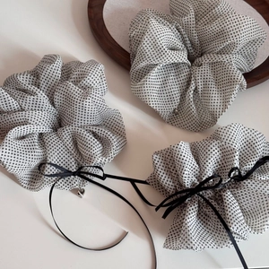 Detailed macro view of white polka dot chiffon scrunchies with black ribbons and heart charms