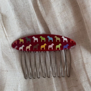 Close-up of colorful horse pattern hair comb with traditional folk art metal teeth