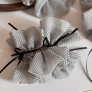 Close-up of white mesh hair scrunchie with black polka dots and a delicate black ribbon bow