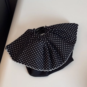 Detailed view of the black and white polka dot fabric bow with a plastic hair claw clip