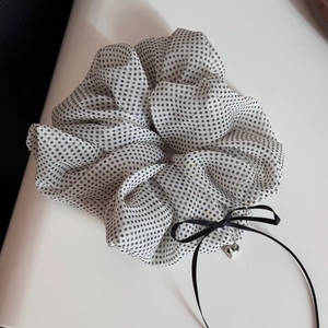 Close-up of chiffon polka dot hair scrunchie with black ribbon and silver heart pendant