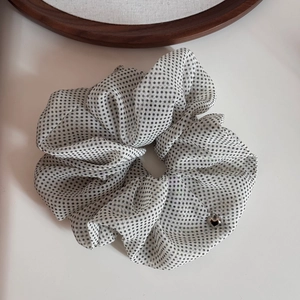 Detailed close-up of a semi-transparent polka dot scrunchie with a silver heart charm