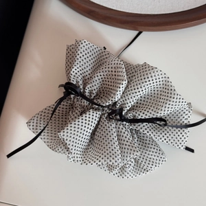 Detailed view of white polka dot chiffon hair scrunchie with a black ribbon bow