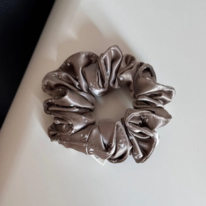 Nahaufnahme des braunen Satin-Haargummis mit Blumenmuster und feiner Stofftextur