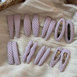 Detail of 14-piece purple polka dot fabric hair clips in various shapes on linen cloth