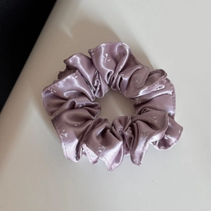 Detailansicht eines lila Satin-Haargummis mit floralem Muster und seidiger Textur