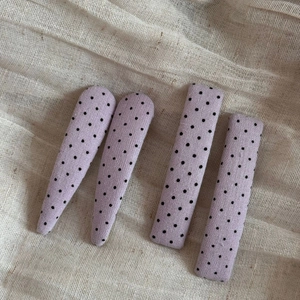 Detailed view of four purple polka dot fabric hair clips in drop and rectangle shapes
