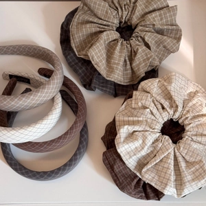 Flat lay of earth-toned checkered fabric hairbands and oversized scrunchies with soft texture