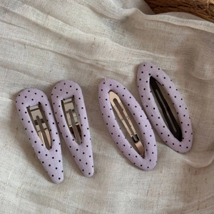 Detailed close-up of 4pcs purple polka dot fabric hair clips on cream linen background