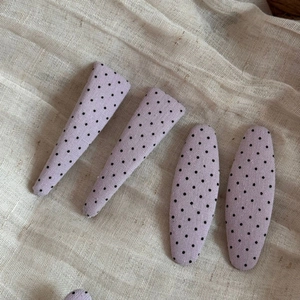 Close-up of four purple polka dot fabric hair clips in triangular and oval shapes