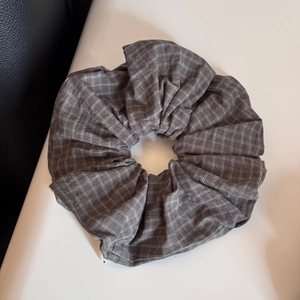Close-up of a grey plaid fabric scrunchie with detailed white checkered pattern