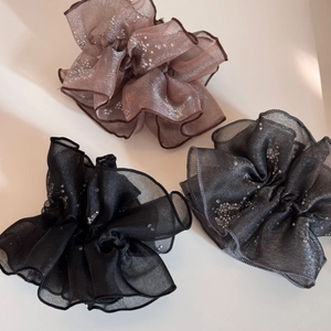 Close-up of sparkling organza scrunchies in pink, black, and grey with fine rhinestones
