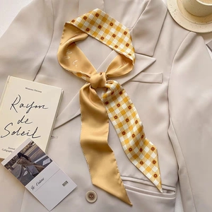 Detail of yellow plaid silk scarf with floral patterns on a beige suit and coffee scene