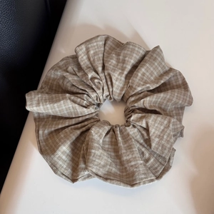 Detail view of the brown plaid fabric texture and elastic structure of the large scrunchie