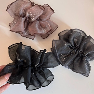 Detailed view of oversized organza scrunchies with glittering silver sequins and pleats