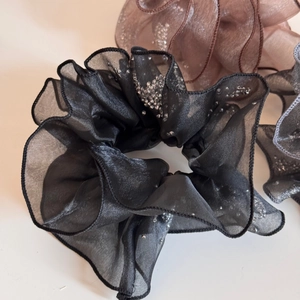 Macro shot of sheer organza scrunchies with subtle sparkles and elegant pleats texture