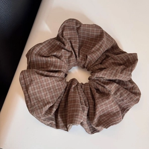 Detailed view of large brown plaid scrunchie with white and orange cross patterns