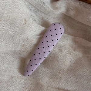 Close-up of purple polka dot fabric hair clip with a coarse linen texture finish