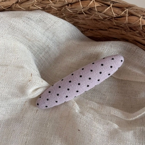 Close-up of a light purple polka dot fabric hair clip inside a rustic straw basket