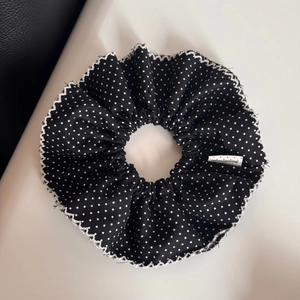 Detailed view of polka dot hair scrunchie with lace edges and a handmade woven label