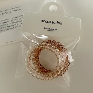 Elastic spiral telephone wire hair ties in amber and brown colors with packaging