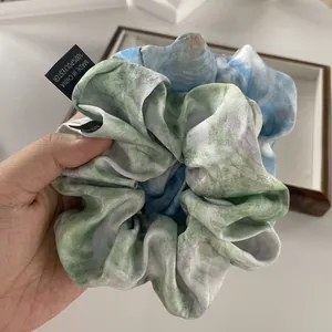 Elegant oversized satin scrunchie featuring an abstract blue and green watercolor ink pattern