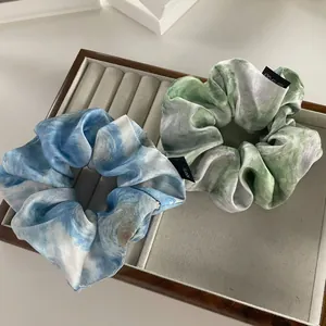 Detail showing marble ink pattern hair scrunchie with 100% polyester fabric texture