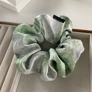 Elegant pleated scrunchie with ink marble pattern in a display tray for hair styling