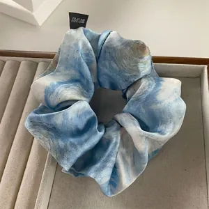 Detailed view of large polyester scrunchie with blue and white watercolor pattern on velvet