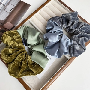 Close-up of luxury velvet and satin patchwork scrunchies with Blind For Love woven labels