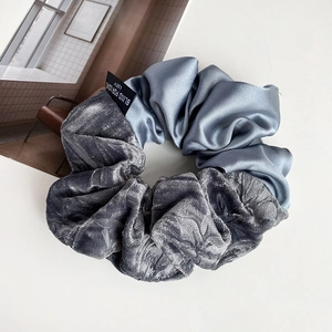 Detail view of French velvet and satin scrunchie with dual texture and brand label