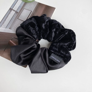 Close-up of black velvet and satin scrunchie with a Made in Korea woven label